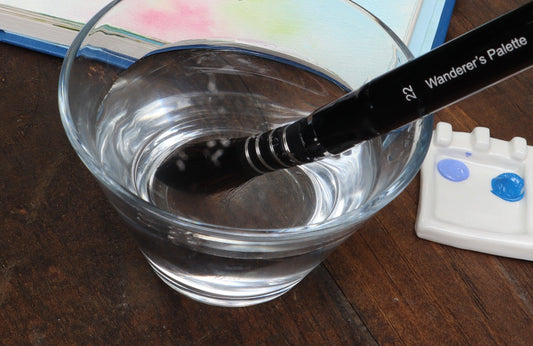 Squirrel mop brush soaking in a glass of water to remove protective sizing